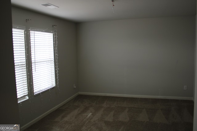 unfurnished room featuring dark carpet