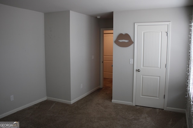 spare room with dark colored carpet