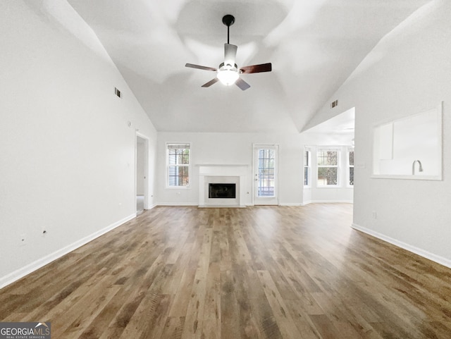 unfurnished living room with ceiling fan, a healthy amount of sunlight, high vaulted ceiling, and hardwood / wood-style floors