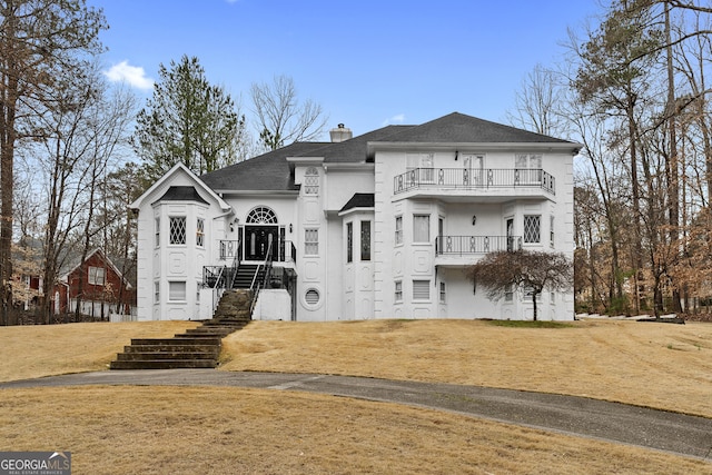 view of front of home with a balcony and a front lawn