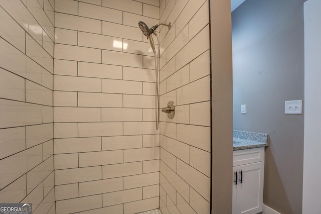 bathroom with tiled shower and vanity