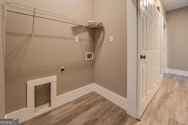 washroom featuring hookup for a washing machine, a fireplace, light hardwood / wood-style floors, and hookup for an electric dryer