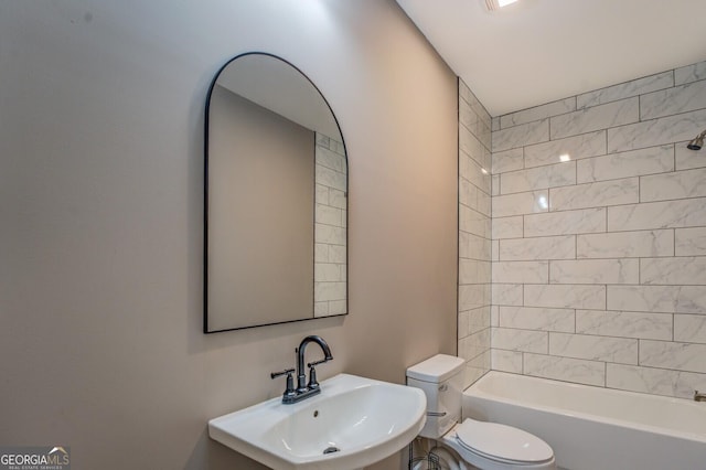 full bathroom with sink, tiled shower / bath, and toilet