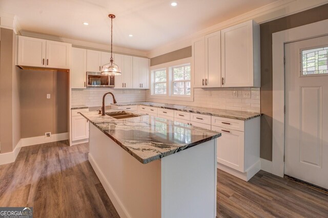 kitchen featuring sink, white cabinets, and a center island with sink