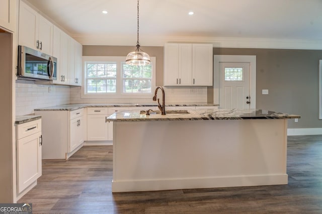 kitchen with a kitchen island with sink, sink, and white cabinets