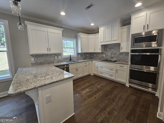 kitchen with appliances with stainless steel finishes, pendant lighting, white cabinets, and kitchen peninsula