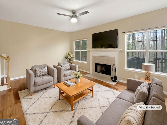 living room with light hardwood / wood-style flooring, a tile fireplace, and a wealth of natural light