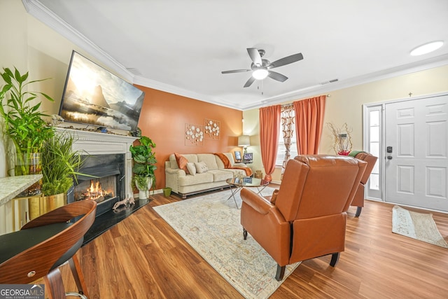 living room featuring hardwood / wood-style flooring, crown molding, and ceiling fan