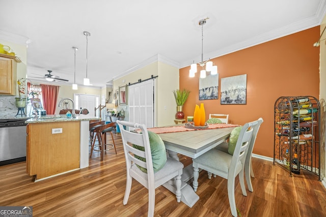 dining space featuring sink, ceiling fan with notable chandelier, dark wood-type flooring, and ornamental molding