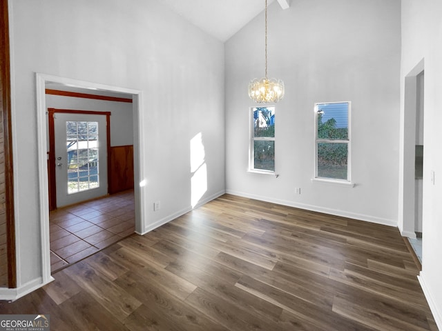 unfurnished dining area with high vaulted ceiling, dark hardwood / wood-style floors, and a chandelier