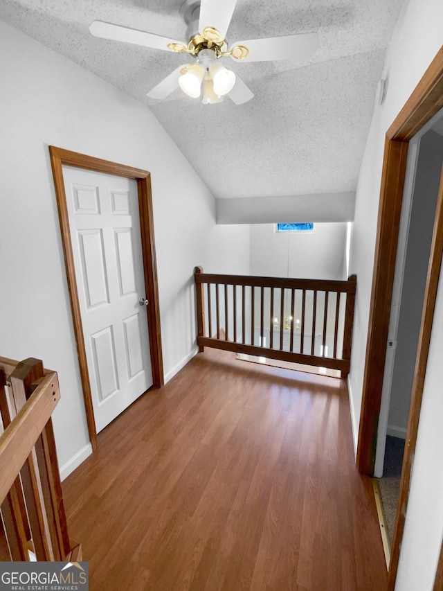 bonus room featuring hardwood / wood-style flooring, ceiling fan, vaulted ceiling, and a textured ceiling