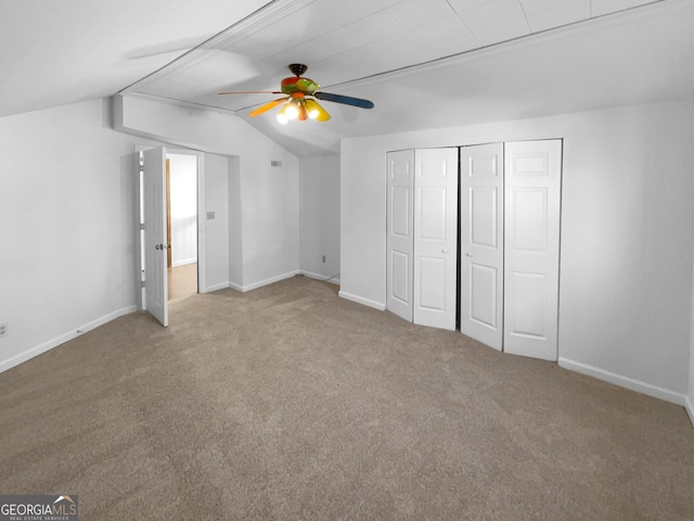 unfurnished bedroom with vaulted ceiling, light colored carpet, a closet, and ceiling fan