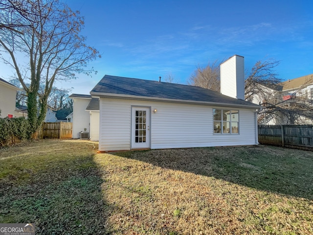 back of property with central AC unit and a lawn