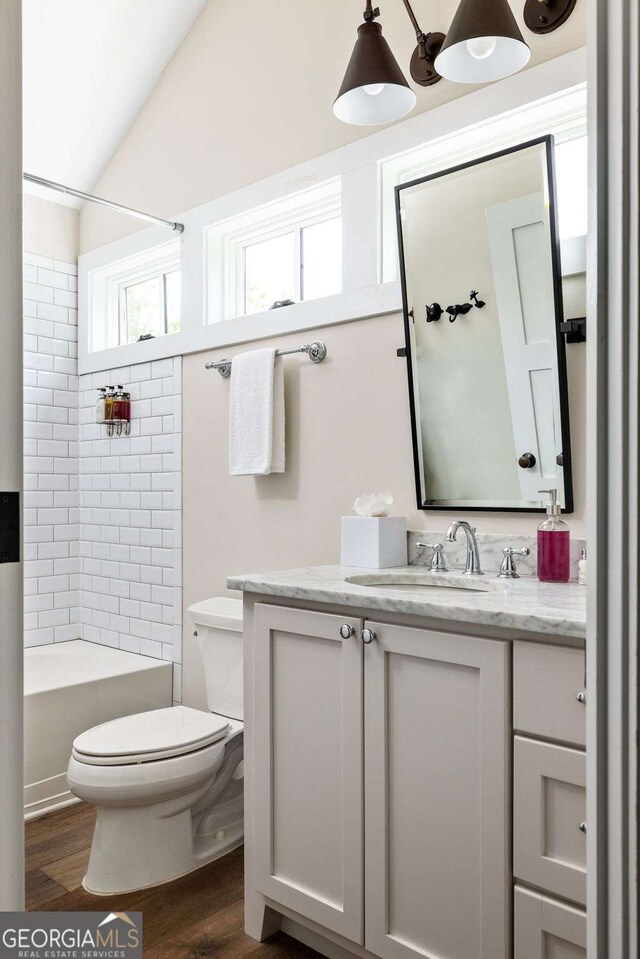 full bath featuring toilet, lofted ceiling, wood finished floors, vanity, and shower / bathing tub combination