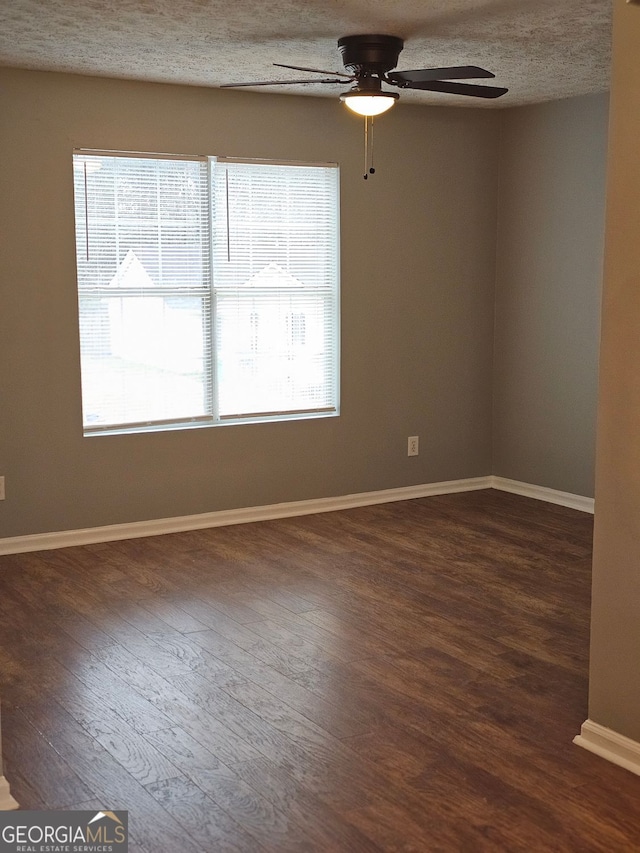 spare room featuring ceiling fan, dark wood-type flooring, and a textured ceiling