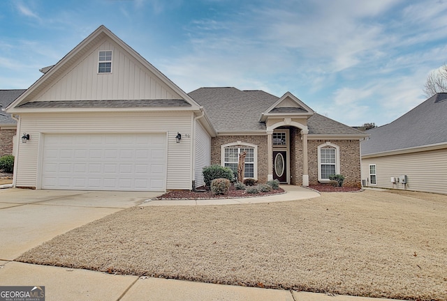 view of front of property with driveway, board and batten siding, an attached garage, a shingled roof, and brick siding