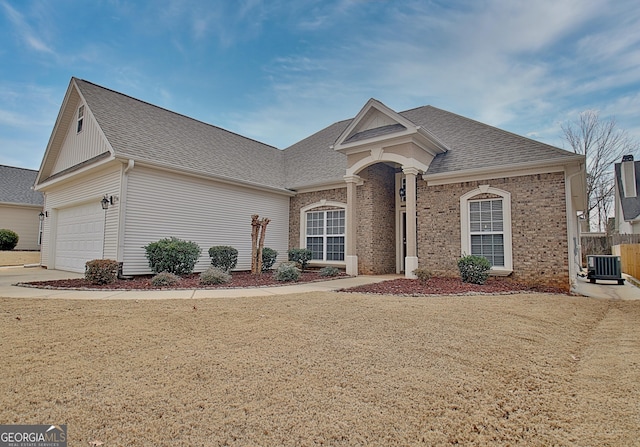 view of front of home with a garage, central AC, and a front lawn