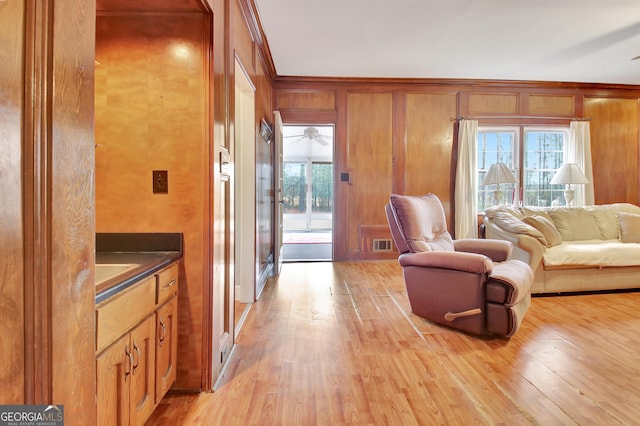 living room with wooden walls, light hardwood / wood-style floors, and a healthy amount of sunlight