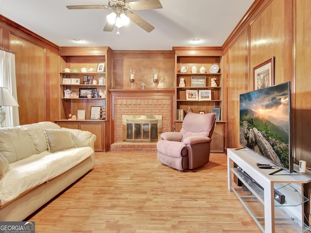 living room featuring a fireplace, light hardwood / wood-style flooring, built in features, and ceiling fan