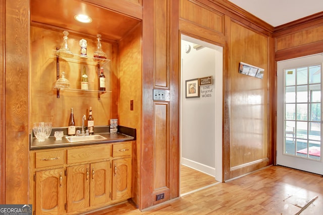 bar featuring ornamental molding, sink, and light wood-type flooring