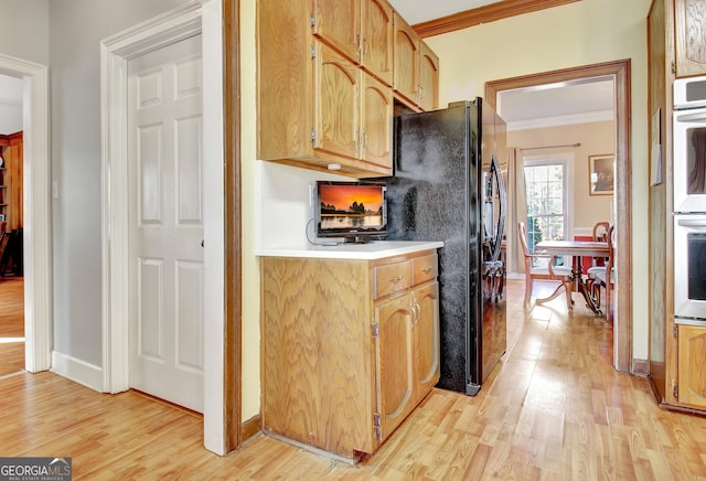 kitchen with double oven, black refrigerator with ice dispenser, ornamental molding, and light hardwood / wood-style floors