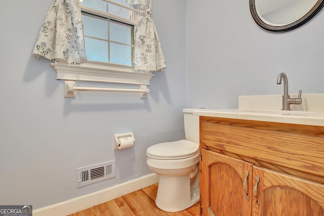 bathroom with vanity, toilet, and hardwood / wood-style floors