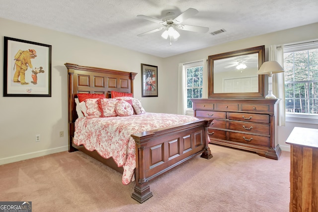 bedroom featuring light carpet, ceiling fan, and a textured ceiling