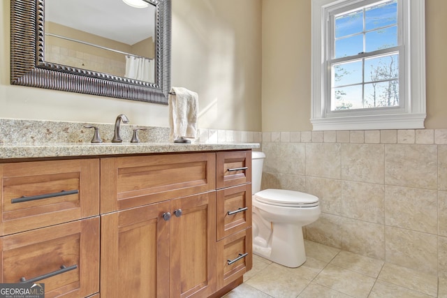 bathroom with tile patterned floors, vanity, toilet, and tile walls