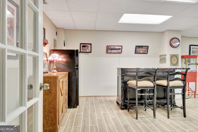 kitchen featuring black fridge, a paneled ceiling, and a kitchen bar