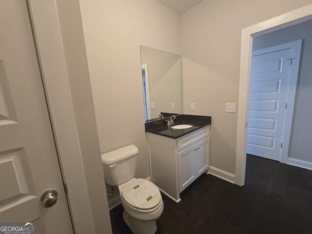 bathroom with hardwood / wood-style flooring, vanity, and toilet