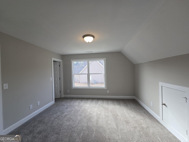 additional living space featuring vaulted ceiling and carpet flooring