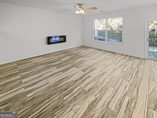 unfurnished living room featuring ceiling fan, a wealth of natural light, and light hardwood / wood-style floors