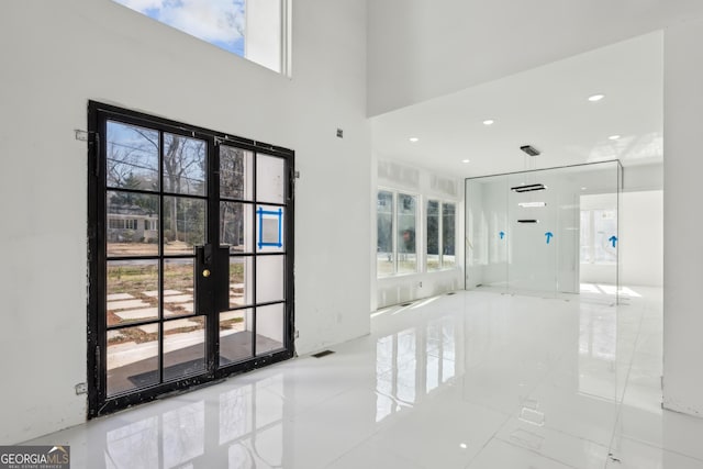 interior space featuring french doors, plenty of natural light, and a high ceiling