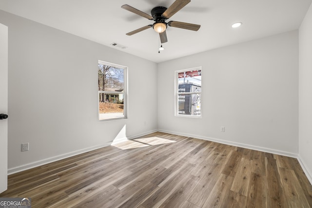 unfurnished room with hardwood / wood-style flooring, ceiling fan, and a healthy amount of sunlight