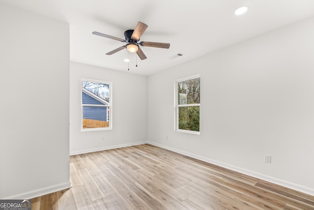 spare room featuring ceiling fan, a healthy amount of sunlight, and light wood-type flooring