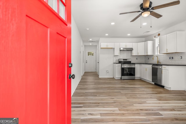 kitchen featuring white cabinetry, appliances with stainless steel finishes, light wood-type flooring, and backsplash