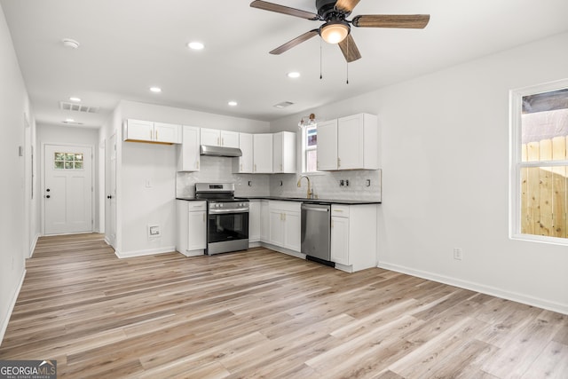 kitchen with white cabinetry, appliances with stainless steel finishes, light hardwood / wood-style flooring, and backsplash