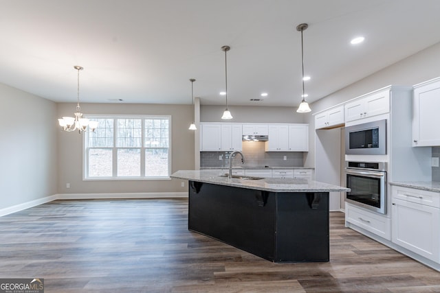 kitchen featuring built in microwave, sink, white cabinets, stainless steel oven, and light stone countertops