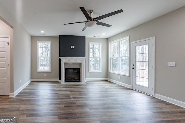 unfurnished living room featuring dark hardwood / wood-style flooring, a healthy amount of sunlight, and a high end fireplace