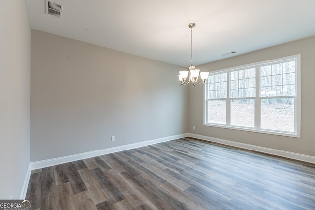 unfurnished room featuring dark wood-type flooring and a notable chandelier