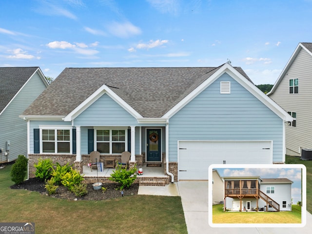 view of front of property with central AC unit, a garage, a front lawn, and covered porch