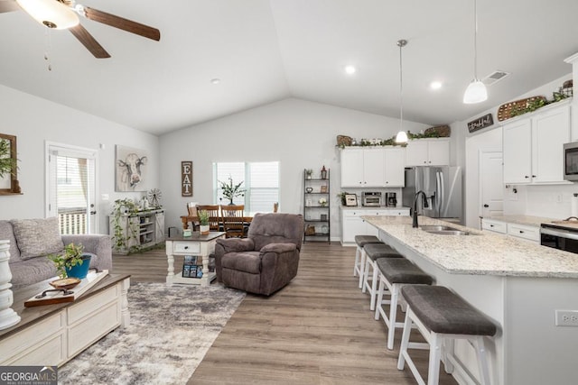 living area featuring light wood finished floors, visible vents, lofted ceiling, recessed lighting, and a ceiling fan