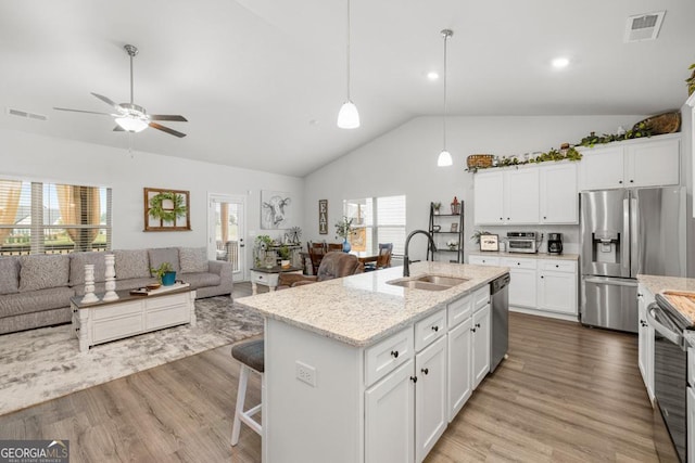 kitchen with visible vents, stainless steel appliances, open floor plan, and a sink