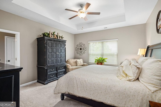 bedroom featuring light colored carpet, a raised ceiling, and ceiling fan