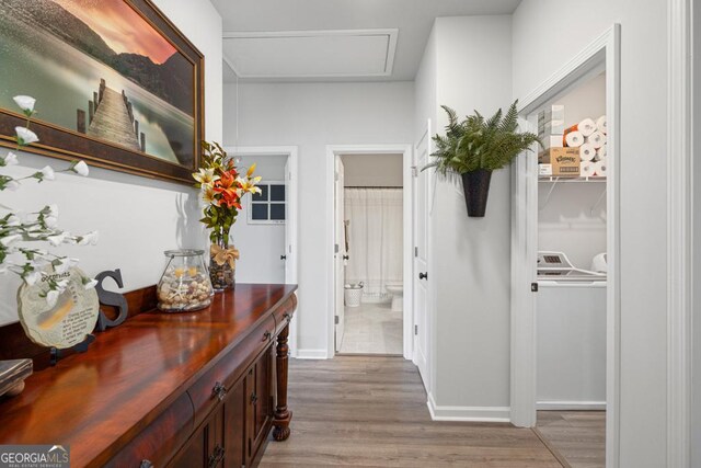 hallway with light wood-style floors, baseboards, and washer and clothes dryer