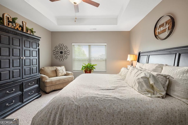 bedroom with ceiling fan, a raised ceiling, visible vents, and light carpet