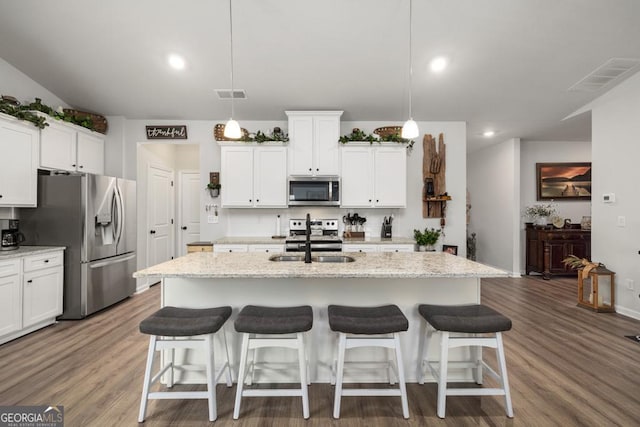 kitchen with a kitchen island with sink, hanging light fixtures, sink, and appliances with stainless steel finishes