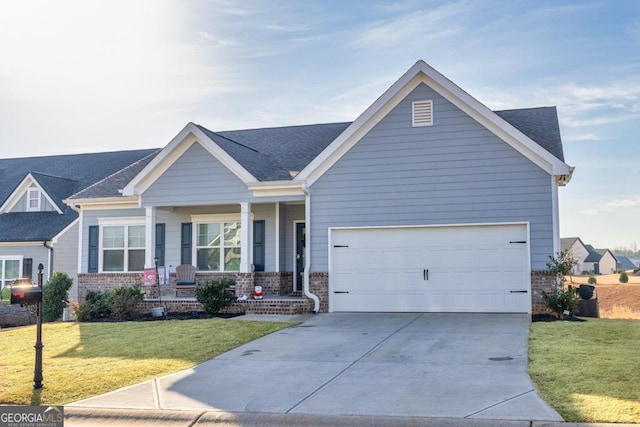 view of front facade with a front yard, a porch, a shingled roof, concrete driveway, and brick siding