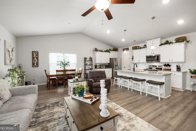 living room with lofted ceiling, recessed lighting, wood finished floors, and ceiling fan