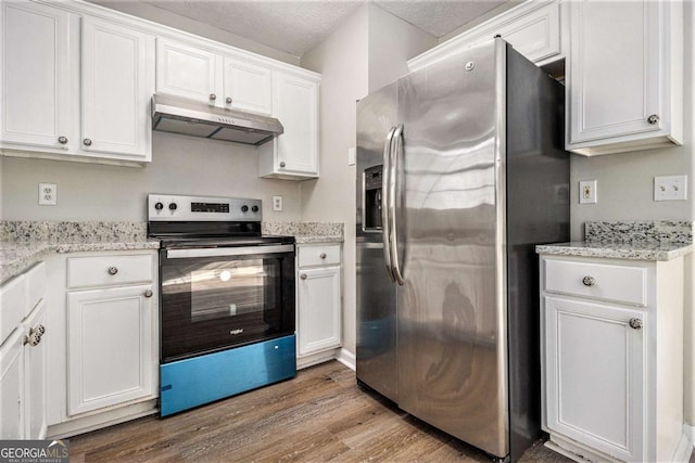 kitchen with appliances with stainless steel finishes, white cabinetry, light stone counters, light hardwood / wood-style floors, and a textured ceiling